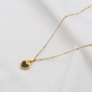 Elegant 18K gold plated titanium necklace with double-sided black heart pendant on white fabric