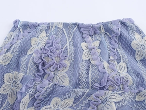 Détail de jupe bohème en dentelle violette avec broderies florales et résille