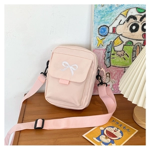 Pink crossbody bag with embroidered bow on the flap and adjustable strap details