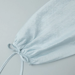 Detailed view of light blue lantern sleeve cuff with drawstring tie and soft texture