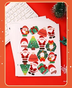 Flat lay of colorful cartoon Christmas stickers featuring Santa and tree on red background