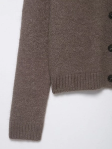 Detail of dark brown knit cardigan showing ribbed cuffs and high-quality wool texture