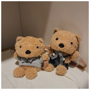 Detail showing two plush teddy bear crossbody bags in grey hoodie and denim overalls