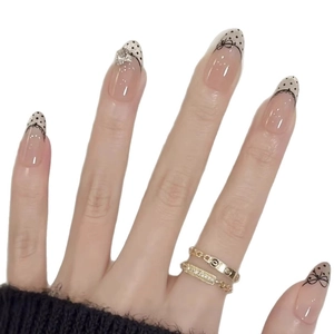 Press-on nails in pink with black polka dots, French tips and 3D rhinestone accents