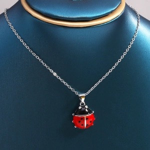Macro shot of red and black ladybug pendant necklace on a jewelry display neck