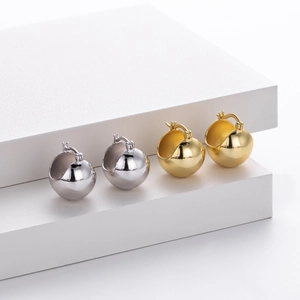 Close-up of gold and silver S925 sterling silver ball earrings on white geometric stands