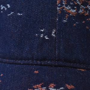 Macro shot of dark blue denim baseball cap featuring orange and white embroidery