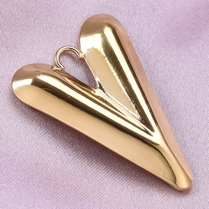 Detail of a polished golden V-shaped pendant with attachment ring on pink fabric background