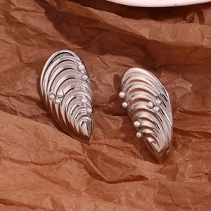 Gros plan de boucles d'oreilles coquillage argentées serties de perles sur papier