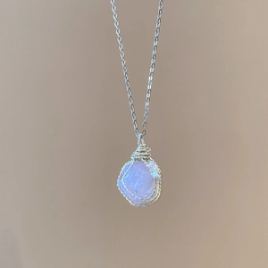 Detail of silver wire wrapped irregular light blue stone pendant on a delicate chain