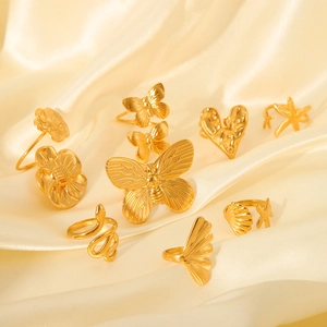 Detailed view of gold butterfly, heart, and starfish rings set on silk fabric