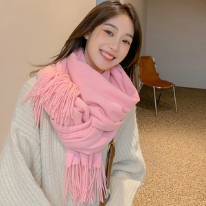 Detailed view of soft pink knitted scarf texture with elegant fringed edges for winter