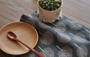 Close-up of linen table mat with tree pattern and lace edge on a rustic wooden table