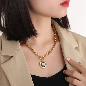 Détail du collier cœur doré avec cristal gris et fermoir à bascule porté par un mannequin