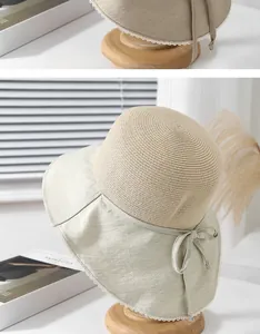 Detail of a straw sun hat with delicate white lace trim and a cotton ribbon bow