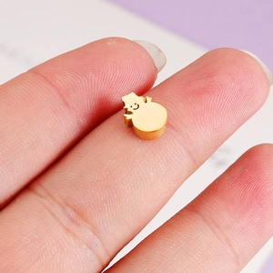 Gold snowman pendant charm in mirror-finish stainless steel shown on fingertip for scale