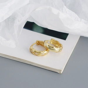 Close-up of gold geometric diamond-set quilted earrings on a white notebook