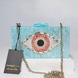 Detail view of light blue marble acrylic clutch bag with large evil eye sequin decoration