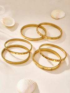 Macro detail of gold plated stainless steel bracelets with zircon inlay and seashell decor