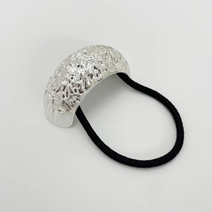 Close-up of textured silver curved alloy accent on black elastic hair tie on white background