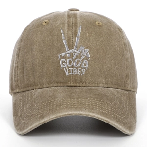 Detailed embroidery of a skeleton hand and Good Vibes on a khaki washed cotton baseball cap