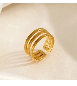 Detail of three-layer gold stainless steel open ring on soft white silk background