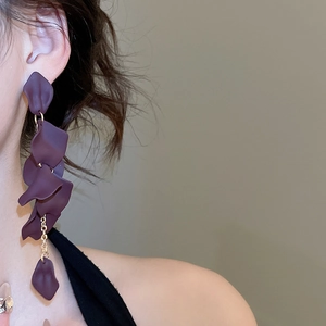 Detailed close-up of matte purple petal earrings with gold chain on model
