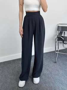 Détail du pantalon large noir à taille haute montrant le drapé et la texture tissée