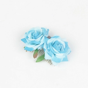 Detail shot of light blue fabric roses and green leaves on a metal hair comb