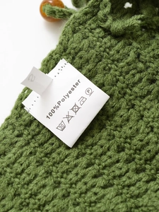 Detail shot of the care label and green crochet fabric showing 100% polyester composition