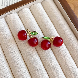 Macro detail of resin cherry earrings with sparkling crystals in a velvet box