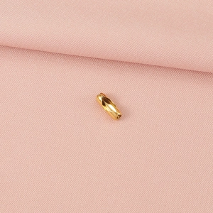 Vue détaillée d'un fermoir de chaîne à billes en métal doré sur tissu rose