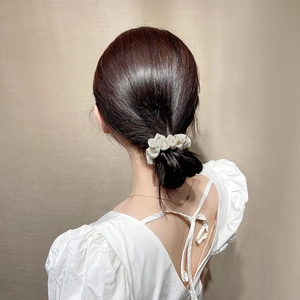 Close-up of a premium satin scrunchie in beige cream worn on a low ponytail