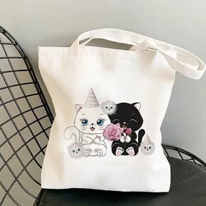 Detail of white canvas tote bag with cute cartoon cat illustrations and sturdy handles