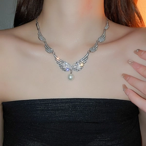Detail of silver angel wing necklace with sparkling zircon and pearl on model neck