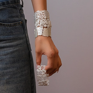Detail of matte silver cuff bracelet featuring hollow floral patterns and molten textures