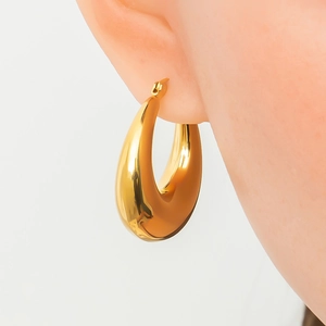 Close-up of elegant oversized gold teardrop thick hoop earrings worn on the ear