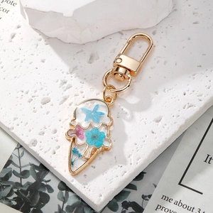 Macro view of ice cream shaped keychain with real dried flowers in resin and gold frame