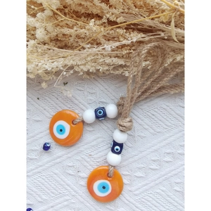 Close-up of handmade orange Evil Eye hanging ornaments with jute rope and beads
