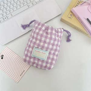 Primer plano de bolsa acolchada de cuadros morados con cordón y bordado de corazón en escritorio