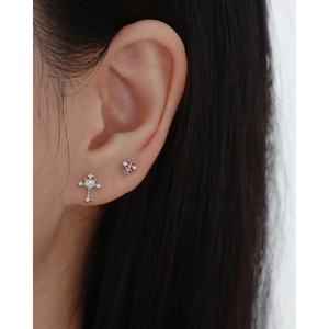 Close-up of s925 silver cross and colorful floral stud earrings on model's ear