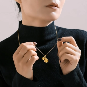 Gold plated stainless steel water drop pendant necklace on a black turtleneck sweater