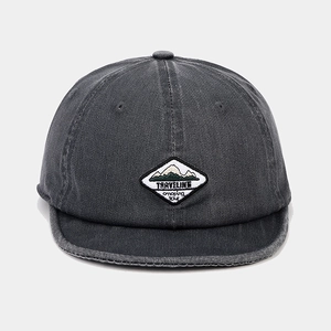 Macro detail of TRAVELINE camping embroidery on a vintage charcoal soft brim cap