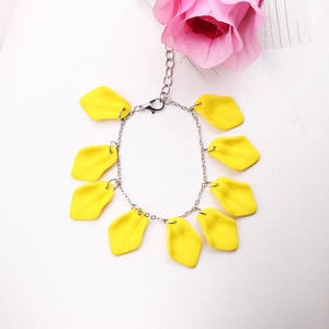 Detail of silver chain bracelet featuring yellow petal charms on a textured background