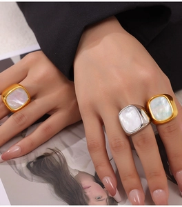 Close-up of three wide gold and silver titanium rings inlaid with white mother of pearl