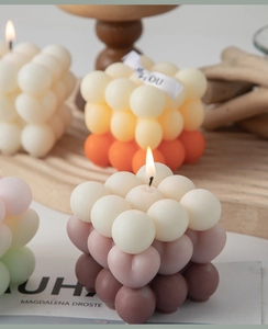 Artistic bubble cube candles in cream, orange and coffee shades on a wooden tray