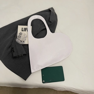 White heart-shaped crocodile pattern shoulder bag on a stylish flat lay background