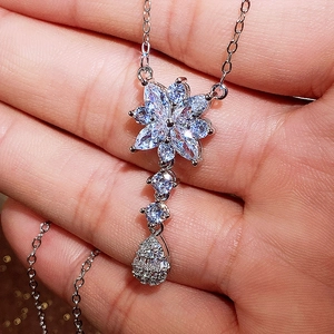 Dettaglio di una collana con fiori e gocce in zircone argento indossata sulla mano