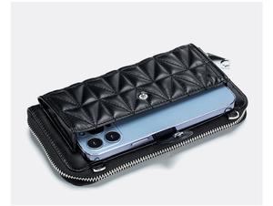Detail view of black leather crossbody phone bag with diamond quilted pattern and zippers