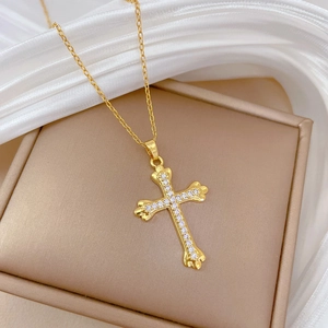 Detail of gold cross pendant with sparkling crystals on a beige jewelry box